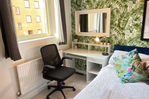 A cozy single bedroom featuring a stylish tropi...
