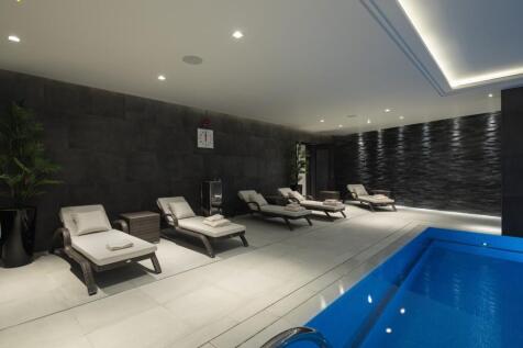 A sleek, modern indoor pool area featuring comf...