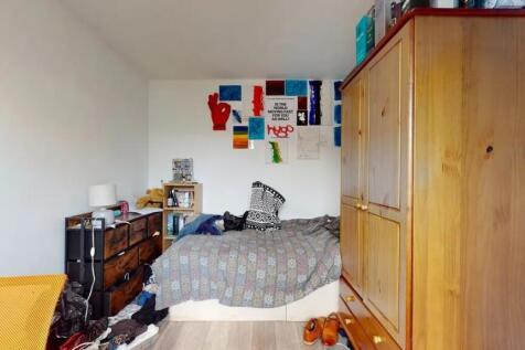 Cozy single bedroom featuring a wooden wardrobe...