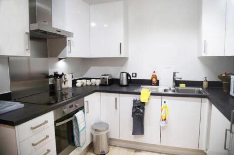 Modern kitchen featuring sleek white cabinets w...