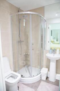 A modern, clean bathroom featuring a curved gla...