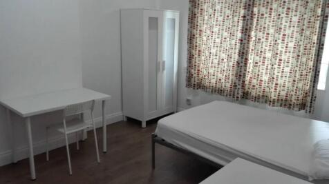 A tidy single bedroom featuring a simple white ...