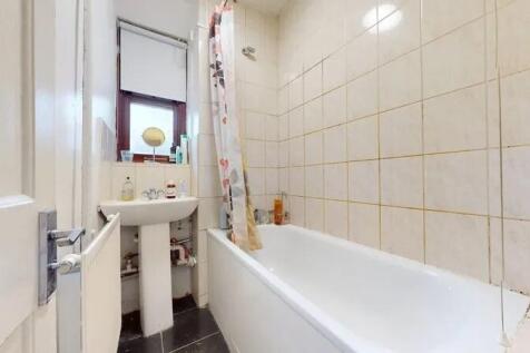 A tidy bathroom featuring a white bath with a p...
