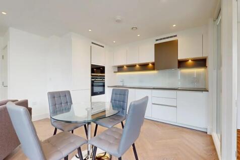 A modern, sleek kitchen featuring white cabinet...