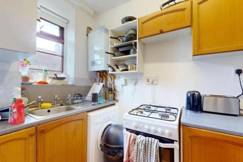 Compact kitchen featuring wooden cabinetry and ...