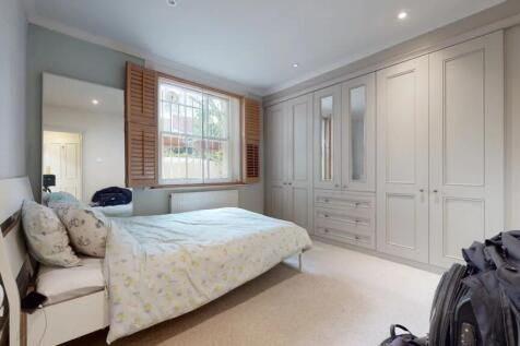 A bright double bedroom featuring a large bed w...