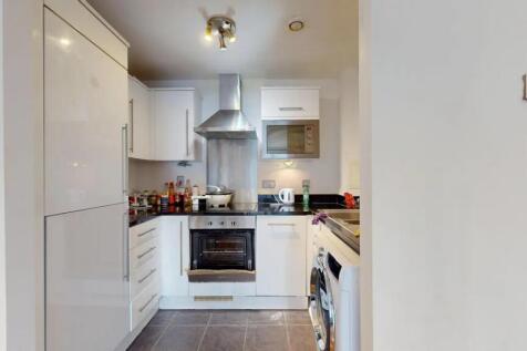 Modern kitchen featuring sleek white cabinetry,...