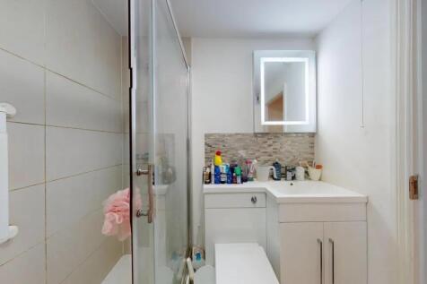 A modern bathroom suite featuring a glass-enclo...