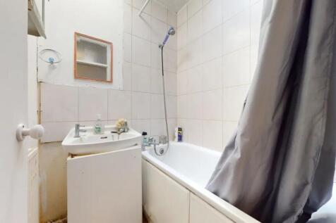 Compact bathroom featuring a bathtub with showe...