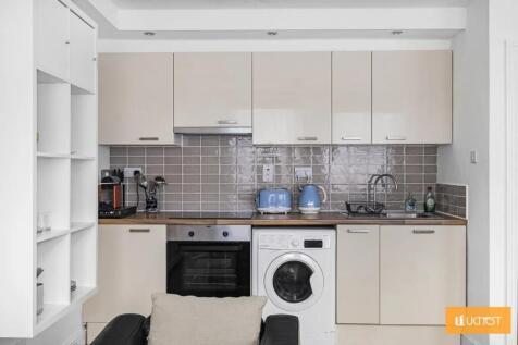 A modern kitchen featuring sleek beige cabinets...