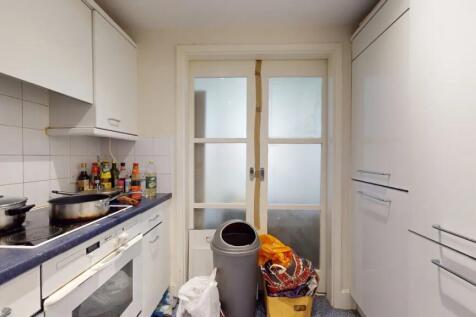 Compact kitchen space featuring white cabinetry...
