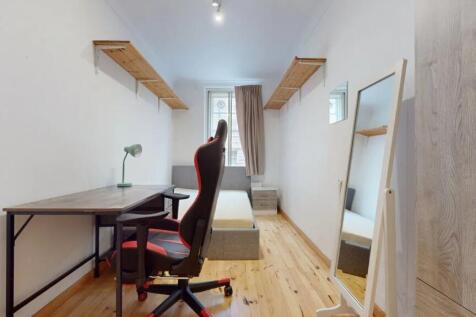 A neat and tidy single bedroom featuring a comf...