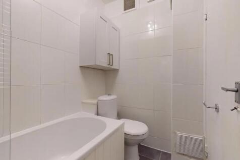 Bright and clean bathroom suite featuring a whi...