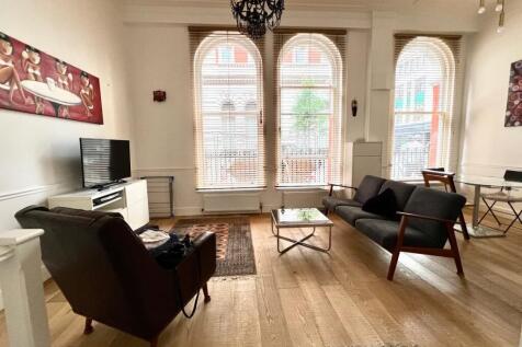 Bright and airy living room featuring large arc...