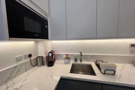 A modern kitchen area featuring sleek white cab...