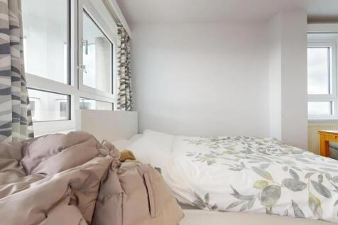 A bright double bedroom with large windows allo...