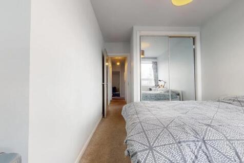 A bright double bedroom featuring a neatly made...