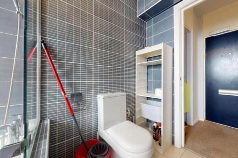A modern single toilet room with sleek grey til...