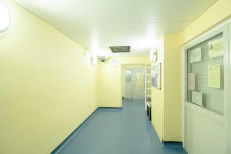 Well-lit hallway with smooth blue flooring and ...