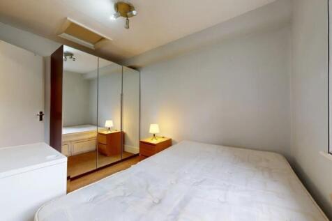 A cozy double bedroom featuring a large bed, mi...