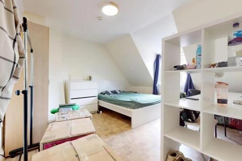 A cozy double bedroom featuring a white bed fra...