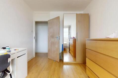 A tidy single bedroom featuring wooden flooring...