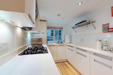 A modern, sleek kitchen featuring white cabinet...