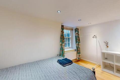 A cozy single bedroom with a neatly made bed, a...