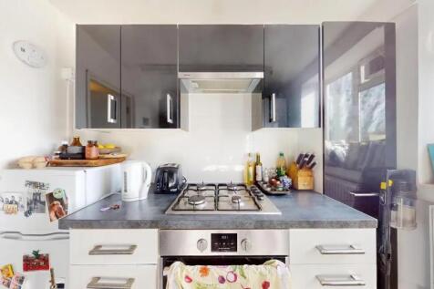 Modern kitchen featuring glossy black cabinets,...