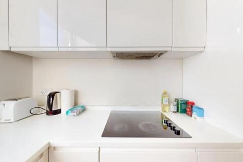 A modern, clean kitchen with sleek white cabine...