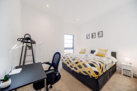 Bright and modern master bedroom featuring a co...