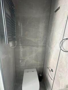 A modern single toilet room featuring sleek gre...