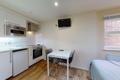A modern, compact kitchen featuring sleek white...
