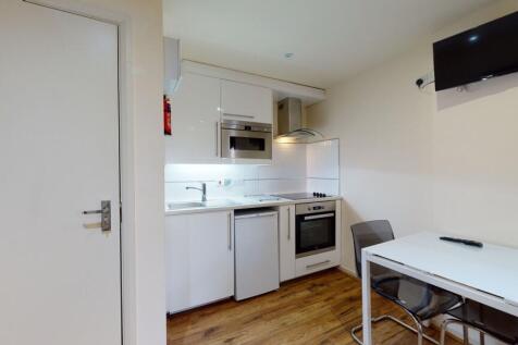 A modern, compact kitchen featuring white cabin...