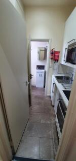 A compact, modern kitchen featuring white cabin...