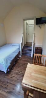 A cozy single bedroom with wooden flooring, a n...