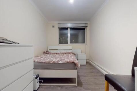 A neat and simple bedroom featuring a white bed...