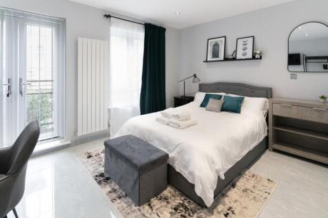 A stylish double bedroom featuring a plush grey...