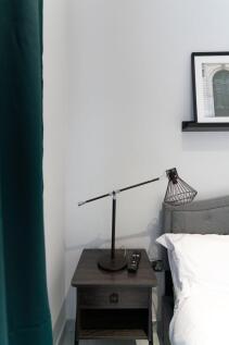 A modern bedside table with a sleek black lamp ...