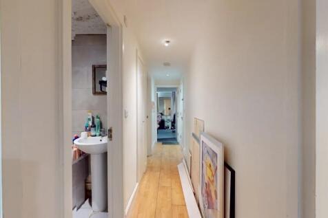 A bright hallway with wood flooring and white w...