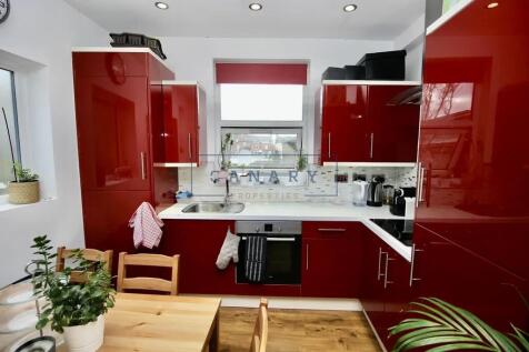Bright modern kitchen featuring glossy red cabi...