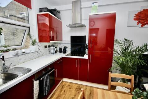 Modern kitchen with glossy red cabinetry, brigh...