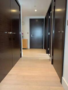 A clean and modern hallway featuring light wood...