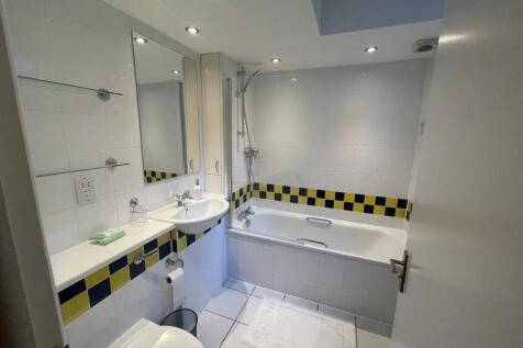 A spacious and bright bathroom featuring a bath...