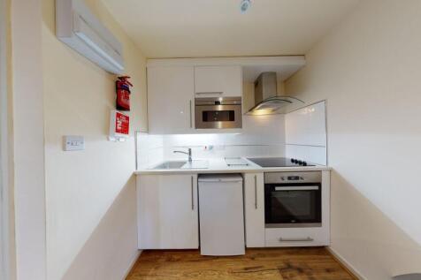 A compact and modern kitchen featuring white ca...