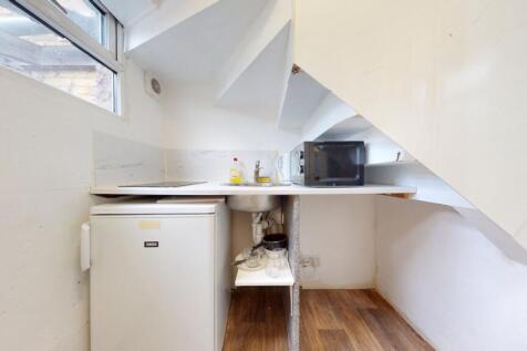 Compact kitchen space featuring a small fridge,...
