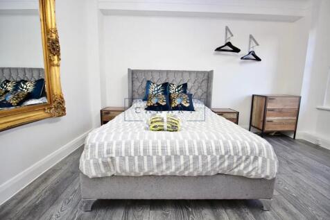 A stylish double bedroom featuring a plush grey...