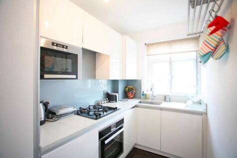 A modern, bright kitchen featuring sleek white ...