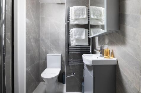 Modern bathroom featuring elegant grey tiles, s...