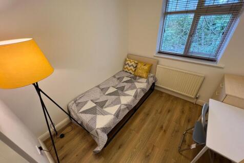 A neat and cozy single bedroom featuring a comf...